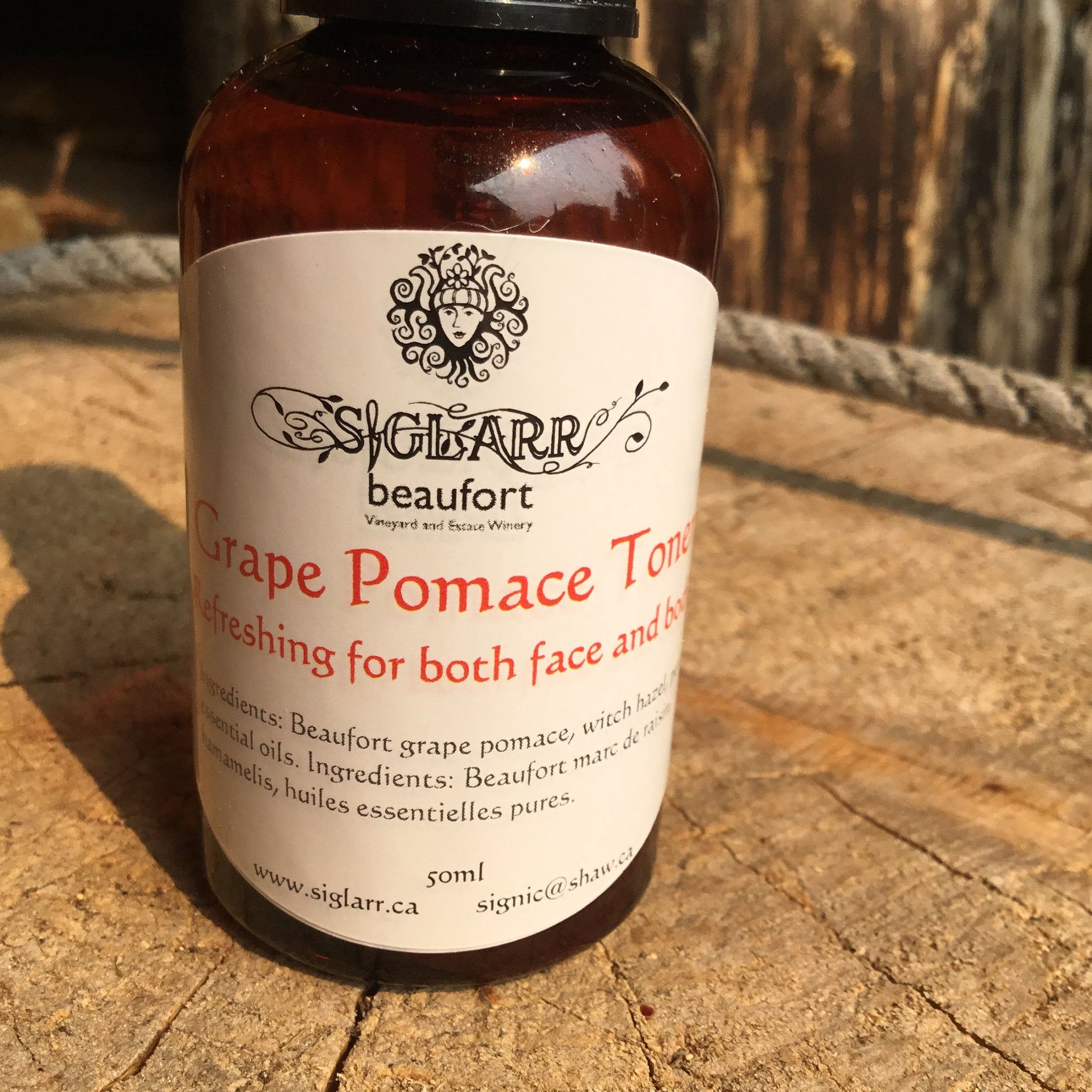Grape Pomace Toner bottle, brown glass, white label with red text, on wood surface.
