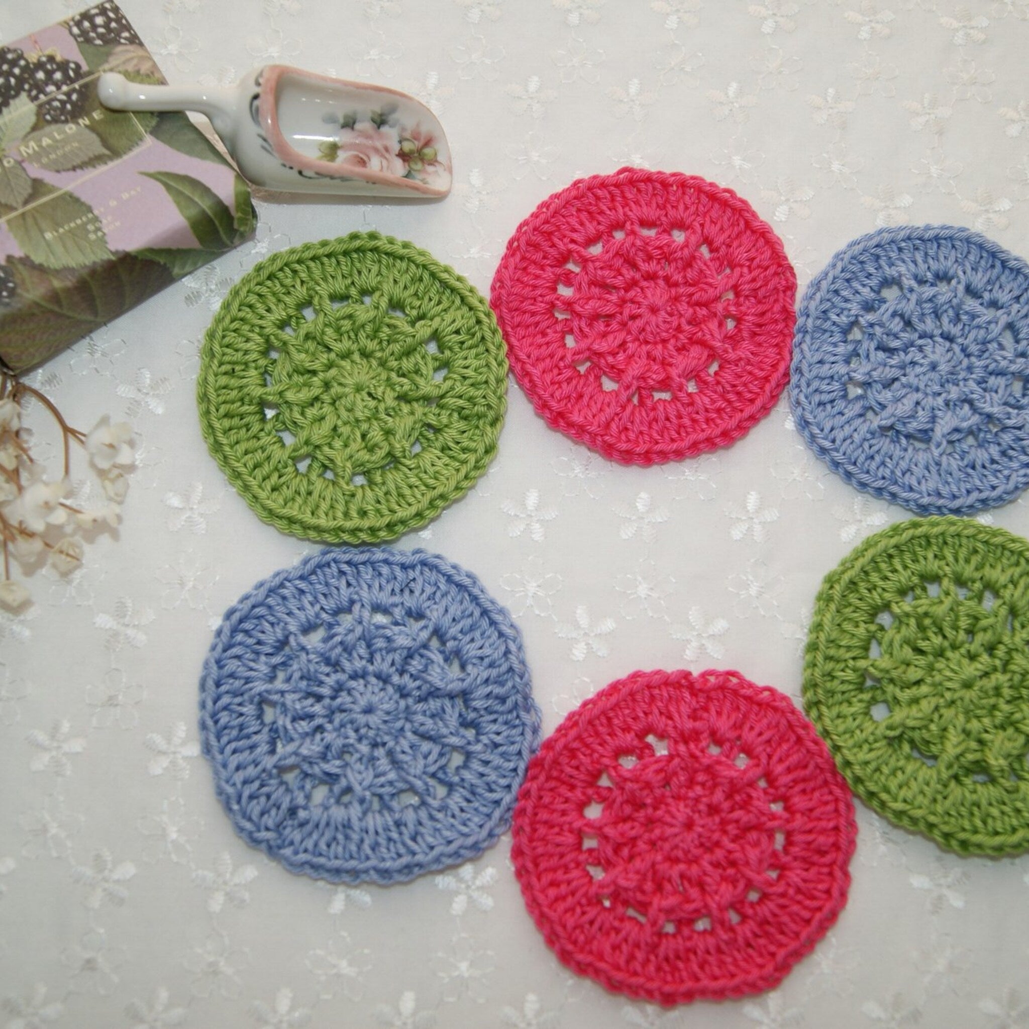 Crochet coasters in green, pink, and blue with openwork pattern, handmade style