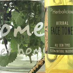 Herbal face toner bottle with green label, yellow liquid, and green leaves in glass