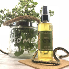 Herbal face toner bottle with yellow liquid, green label, and Herbalicious brand name on a cork mat