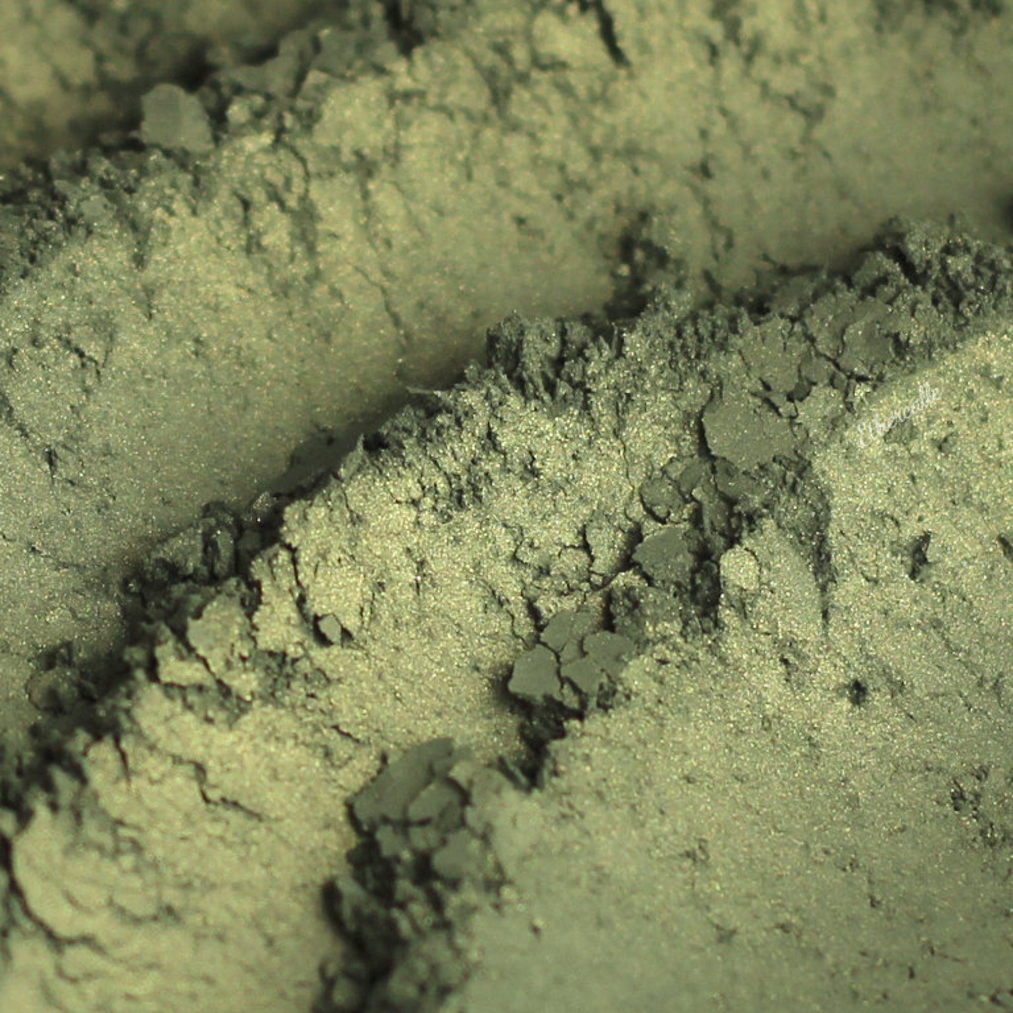 Eyeshadow, green and gold shimmer, textured powder with visible sparkle