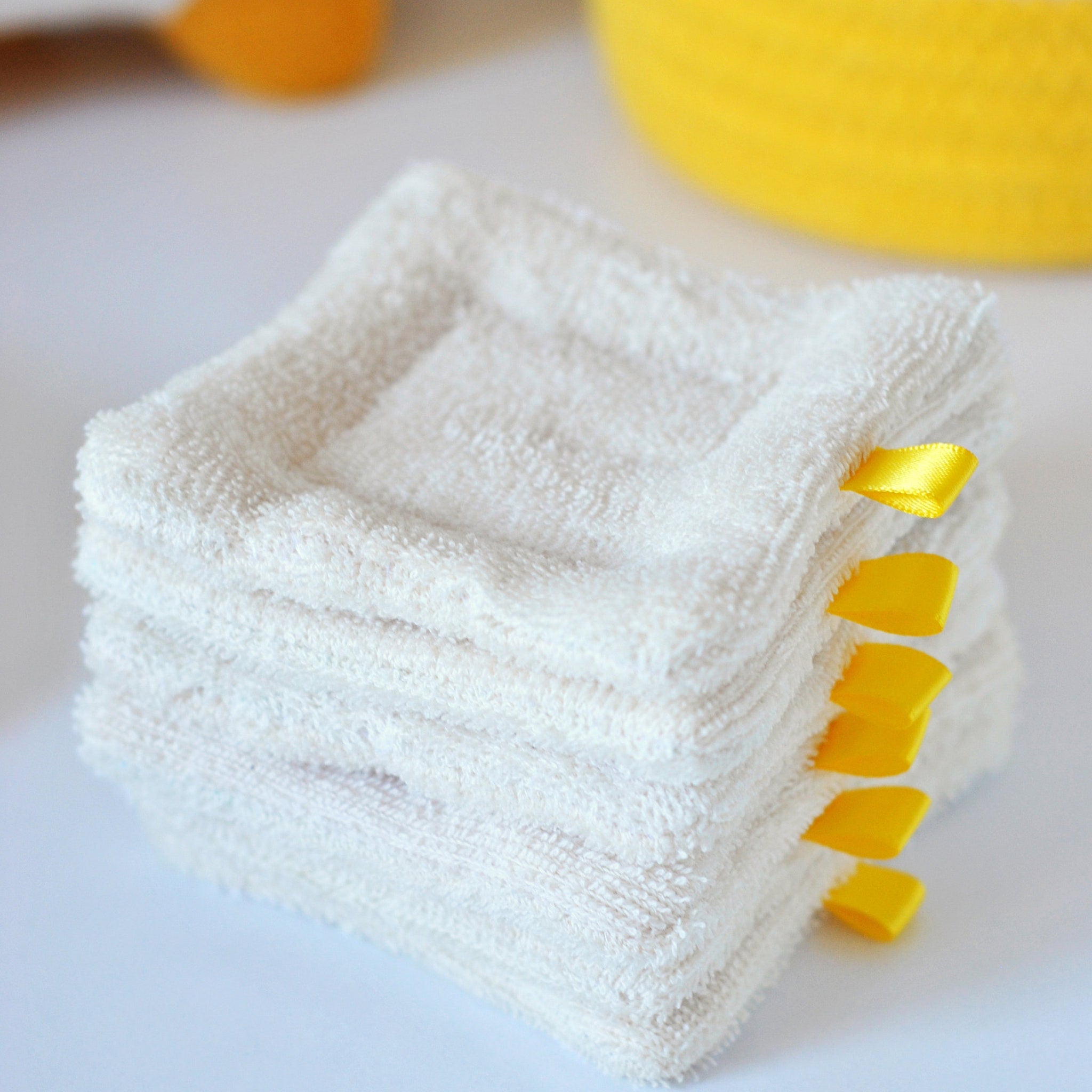 Stack of three organic cotton sponge wipes in soft beige tones, neatly arranged on bamboo tray