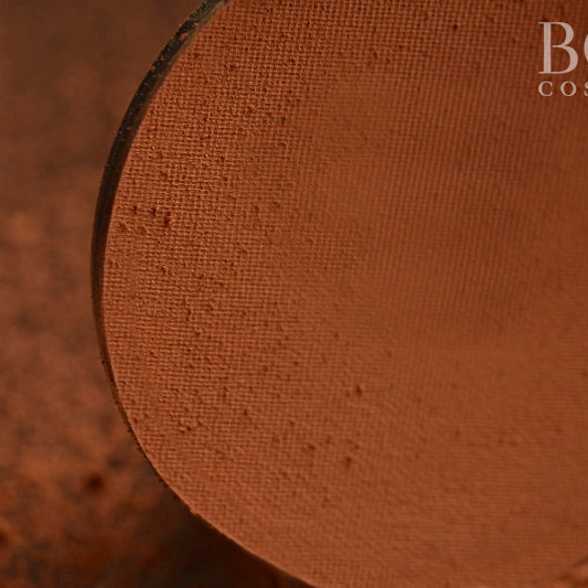 Side view of matte pressed eyeshadow single pan in chic orange and brown tones, showcasing texture and compact shape