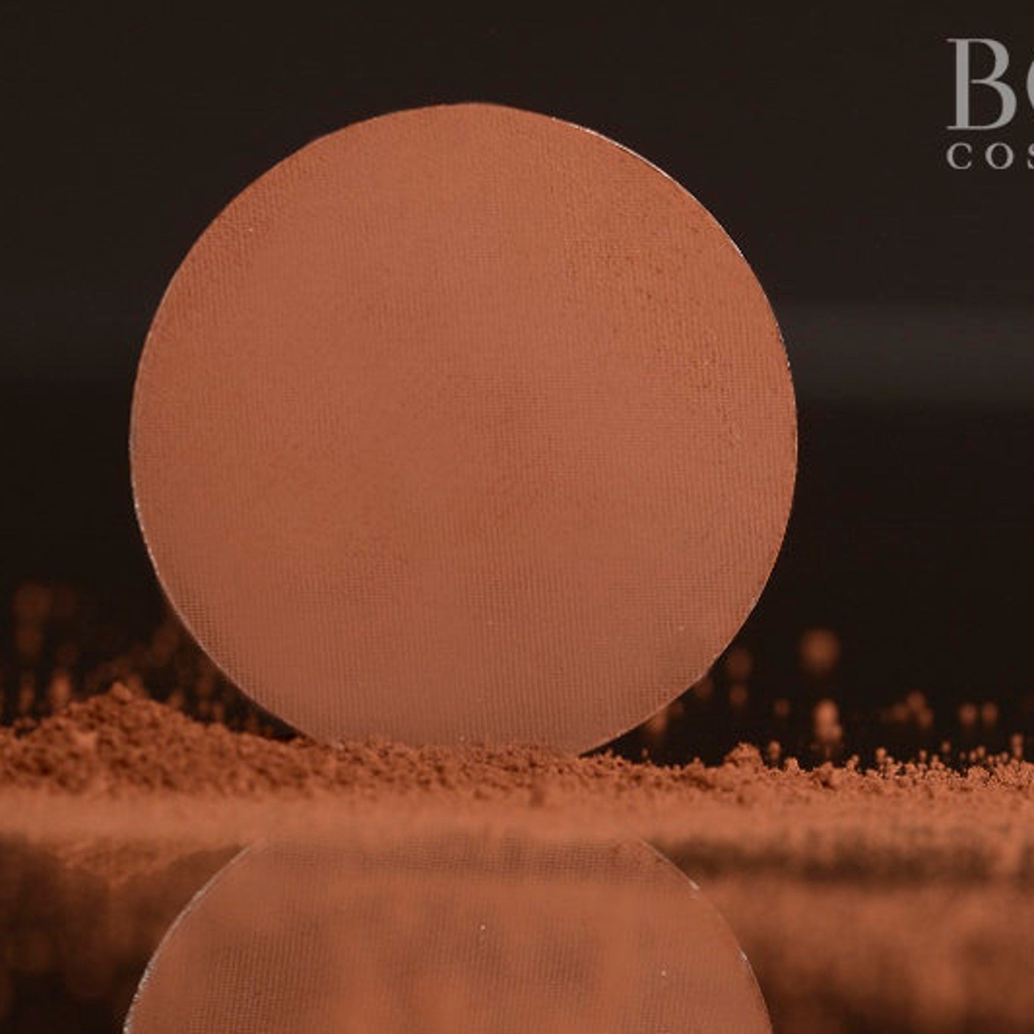 Close-up of pressed matte red-brown eyeshadow in a circular pan with smooth, pigmented texture