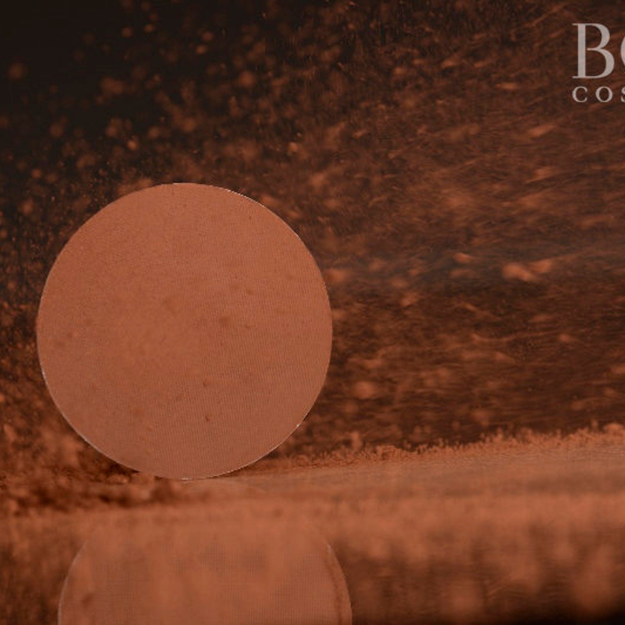 Side view of pressed red-brown matte eyeshadow single pan in 37mm compact showing texture and pigment depth