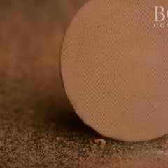 Powder compact with brown color and textured surface, with "B" brand text visible