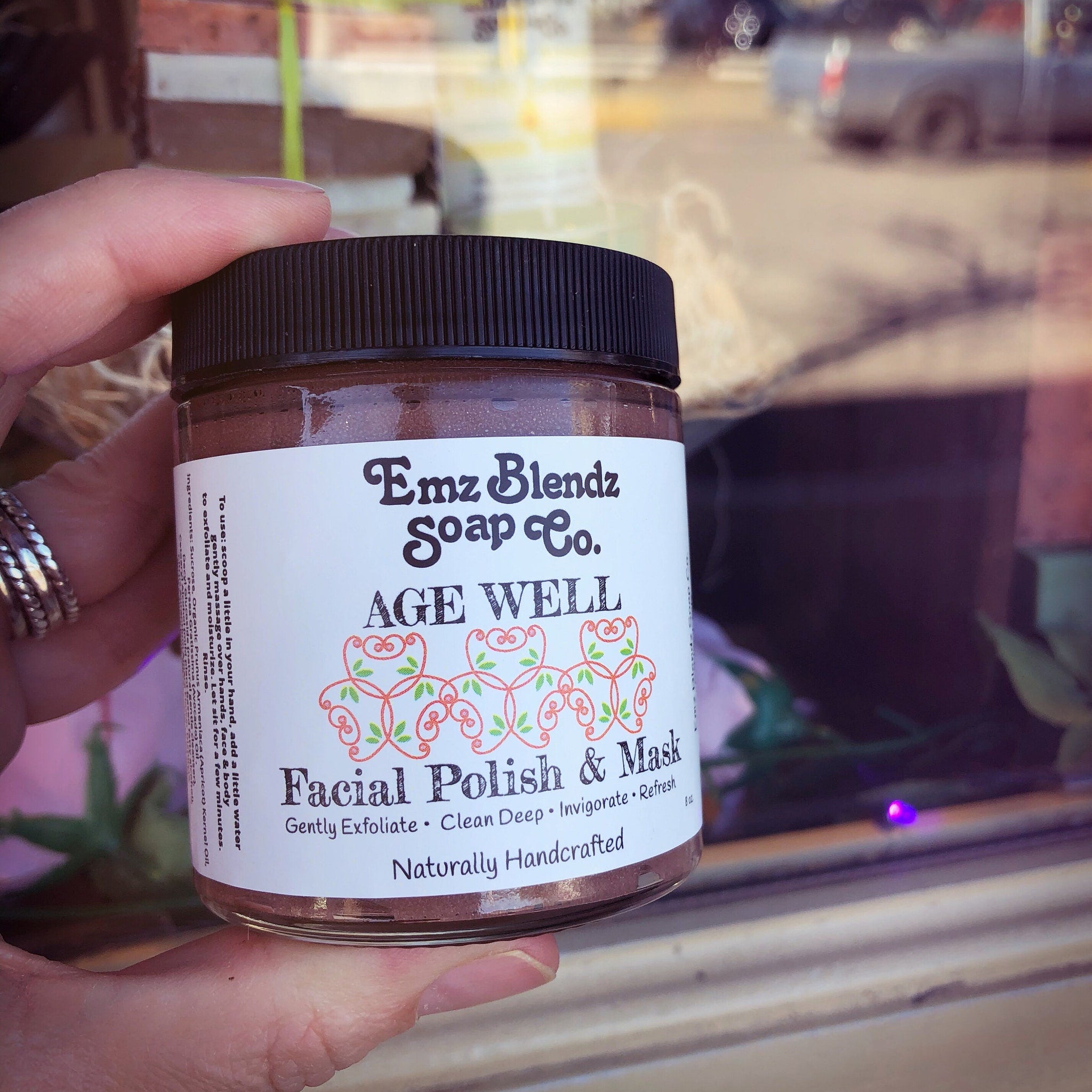 Facial Polish & Mask jar with brown contents, black lid, and white label, held in hand by Emz Blendz Soap Co.
