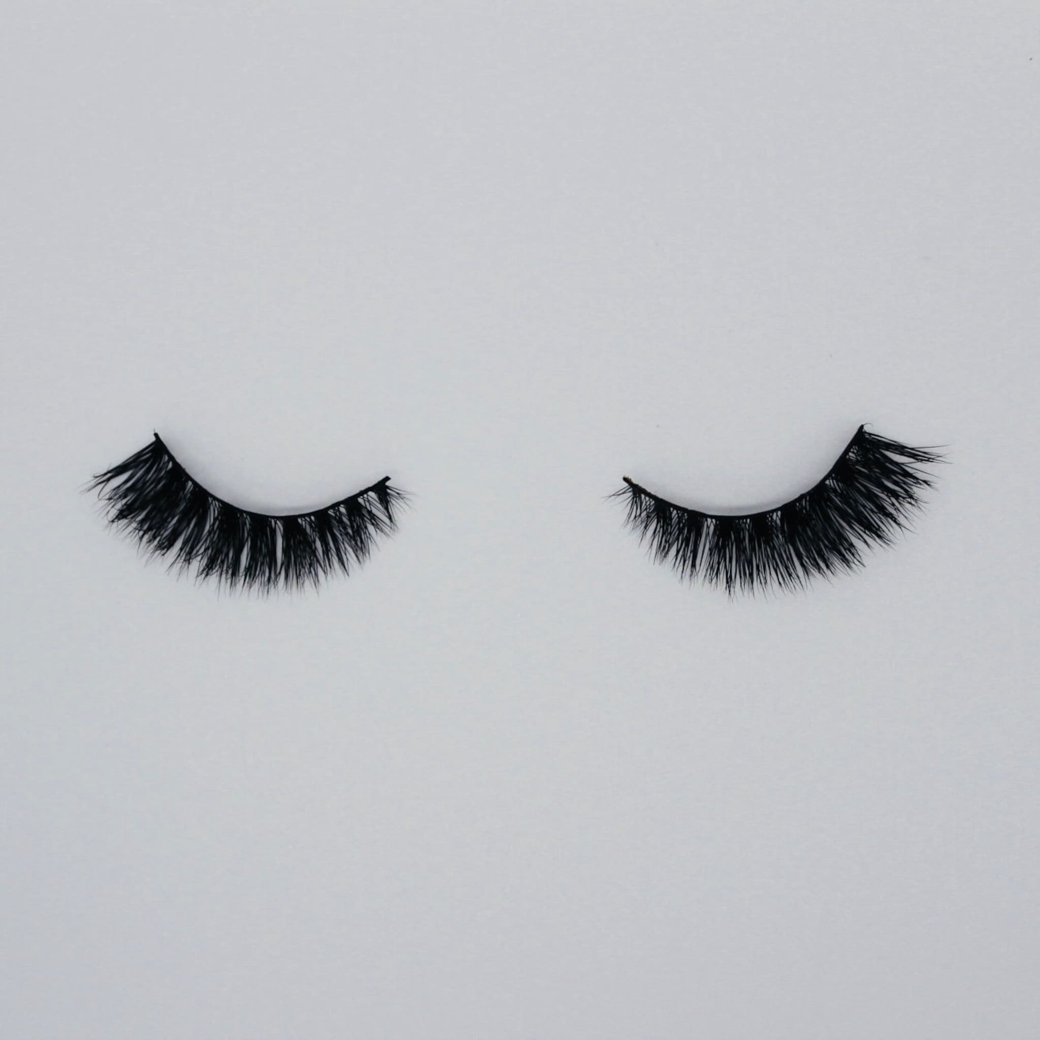 False eyelashes in black with long, wispy fibers on white background