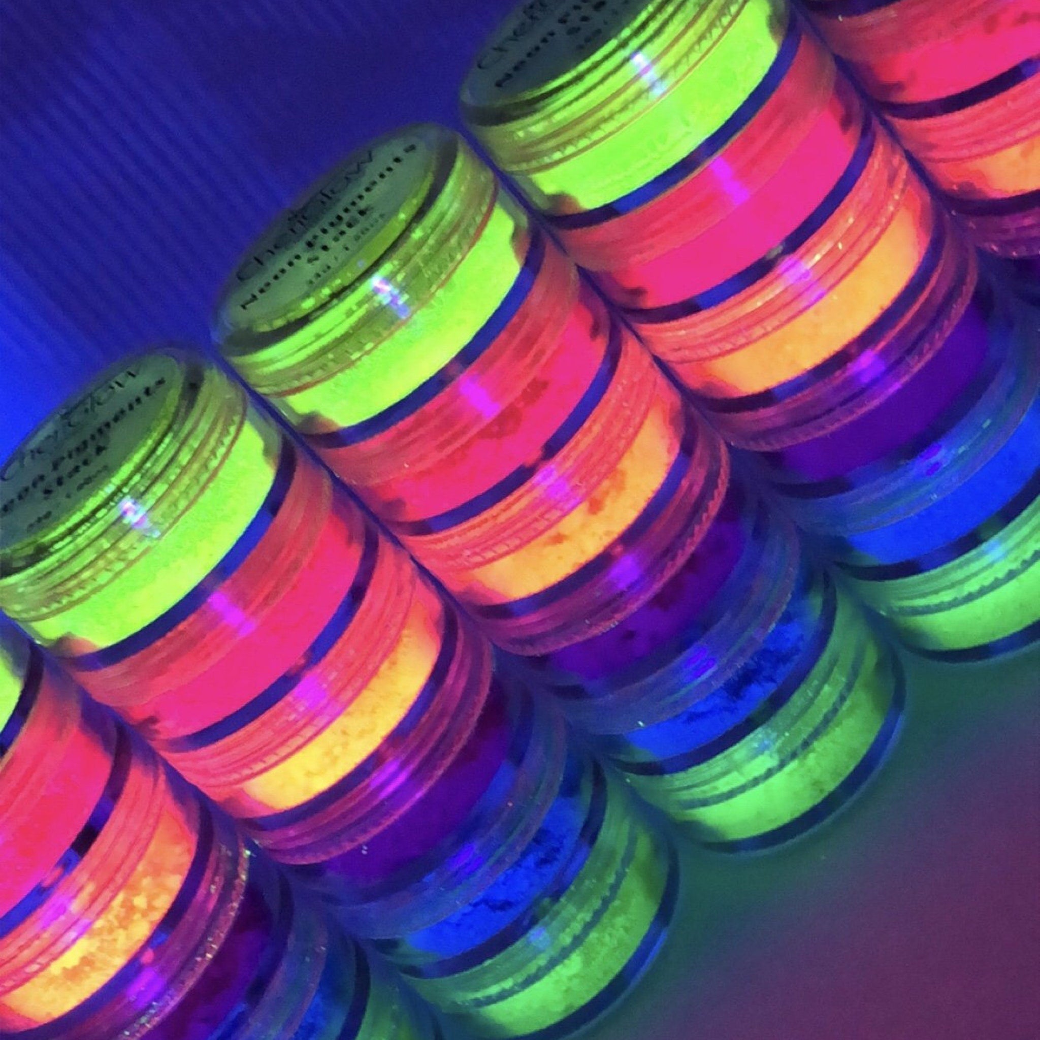 Eye shadows stacked with neon colors, CheriGlowCosmetics brand, in clear jars