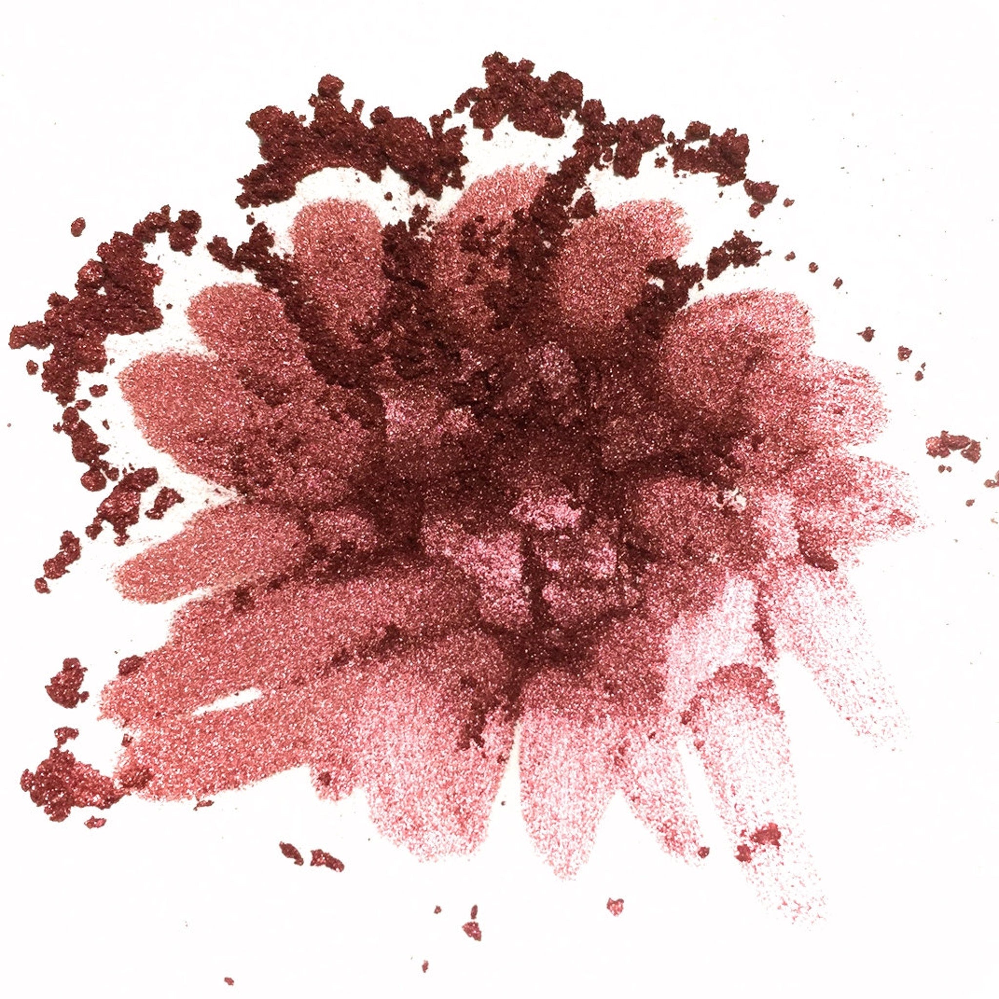 Hand applying shimmering bronze loose powder eyeshadow with a fluffy brush for a soft, blended look