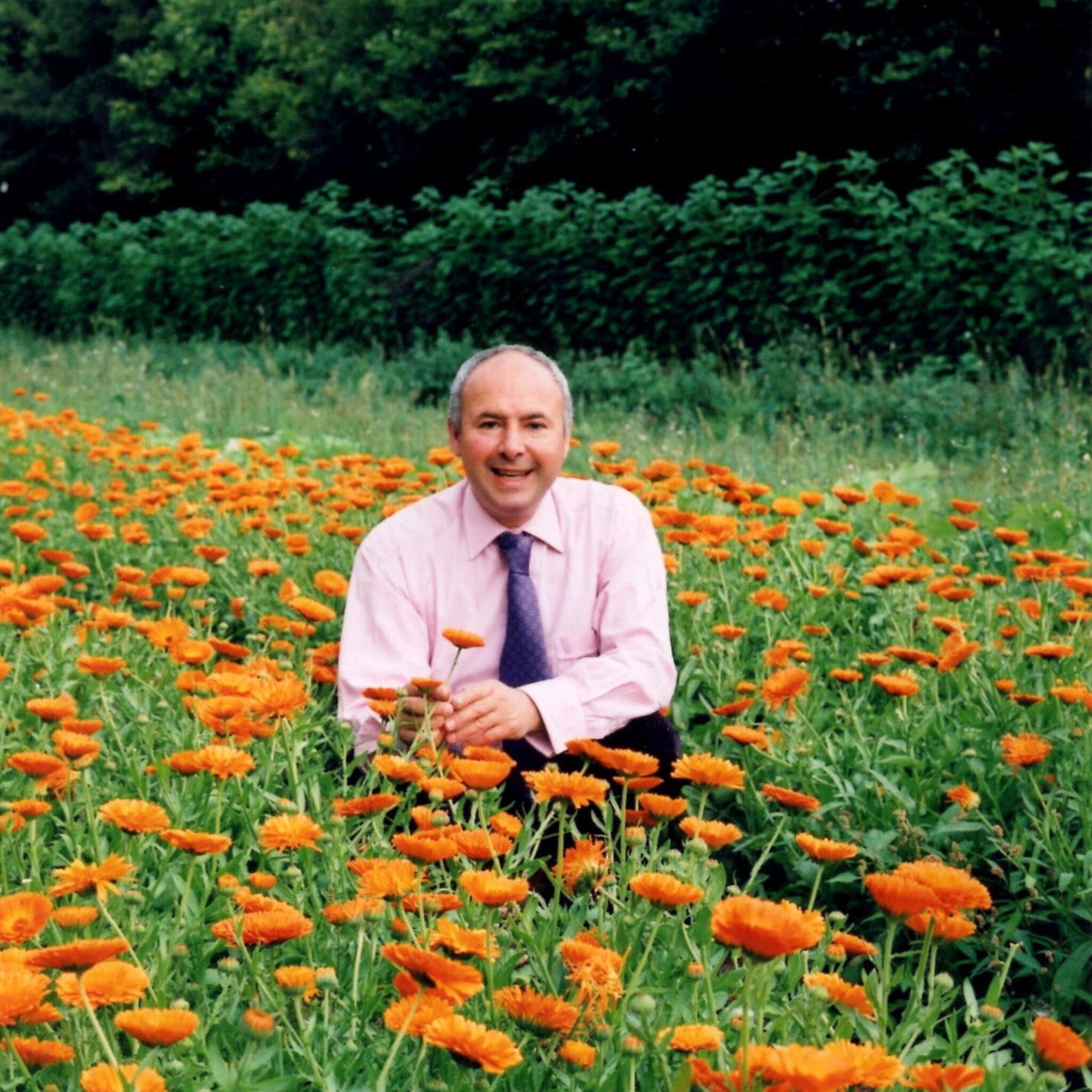 Man in pink shirt and patterned tie with orange flowers in field