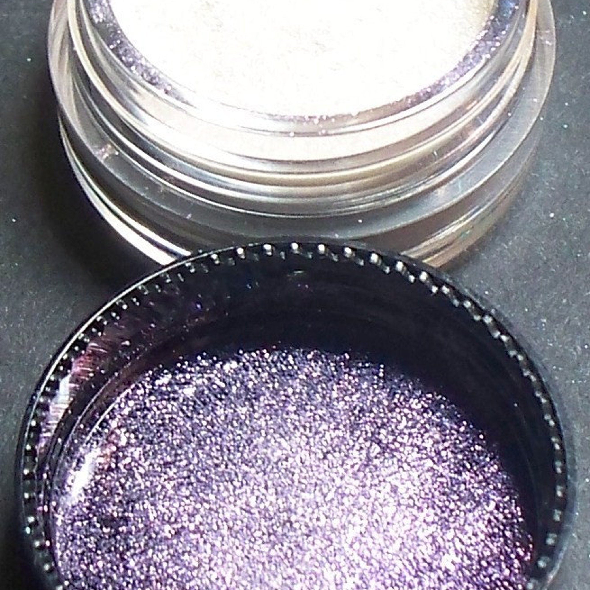 Side view of iridescent purple eyeshadow pan catching light with shimmer particles