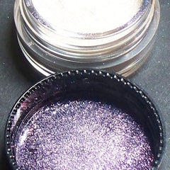 Side view of iridescent purple eyeshadow pan catching light with shimmer particles