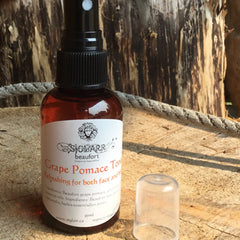 Toner bottle with red liquid, black cap, and white label, "SIGLARR" brand, on wood surface