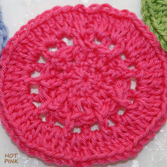 Crocheted circle in hot pink yarn with openwork design and visible texture