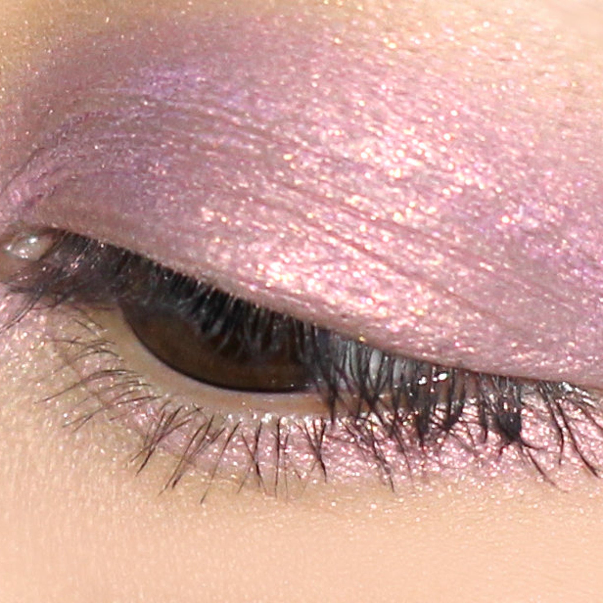 Eyeshadow with shimmering pink color and visible sparkles applied to eyelid