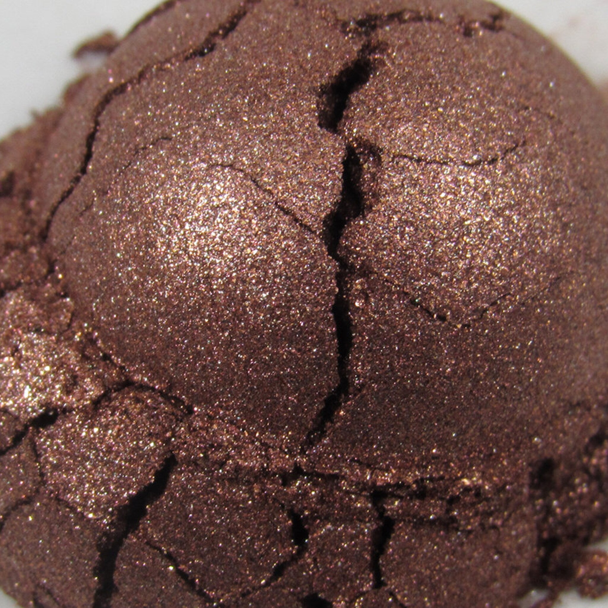 Side view of dark copper brown loose powder eyeshadow with shimmer particles in a sleek glass jar