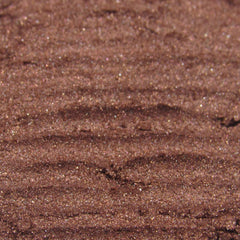 Hand applying shimmering dark copper brown loose powder eyeshadow with a fluffy brush for a smoky eye look