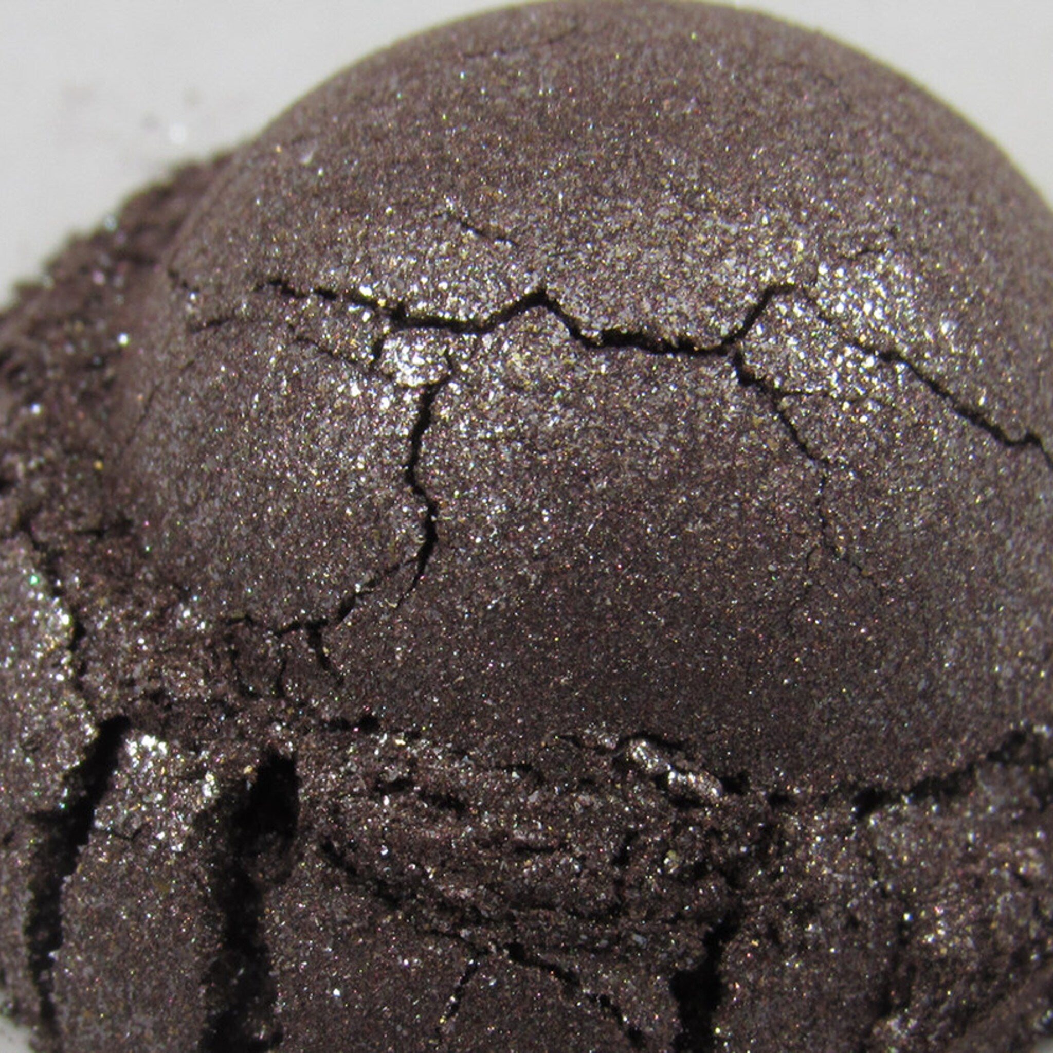 Eyeshadow, dark brown with glitter, cracked texture, close-up view