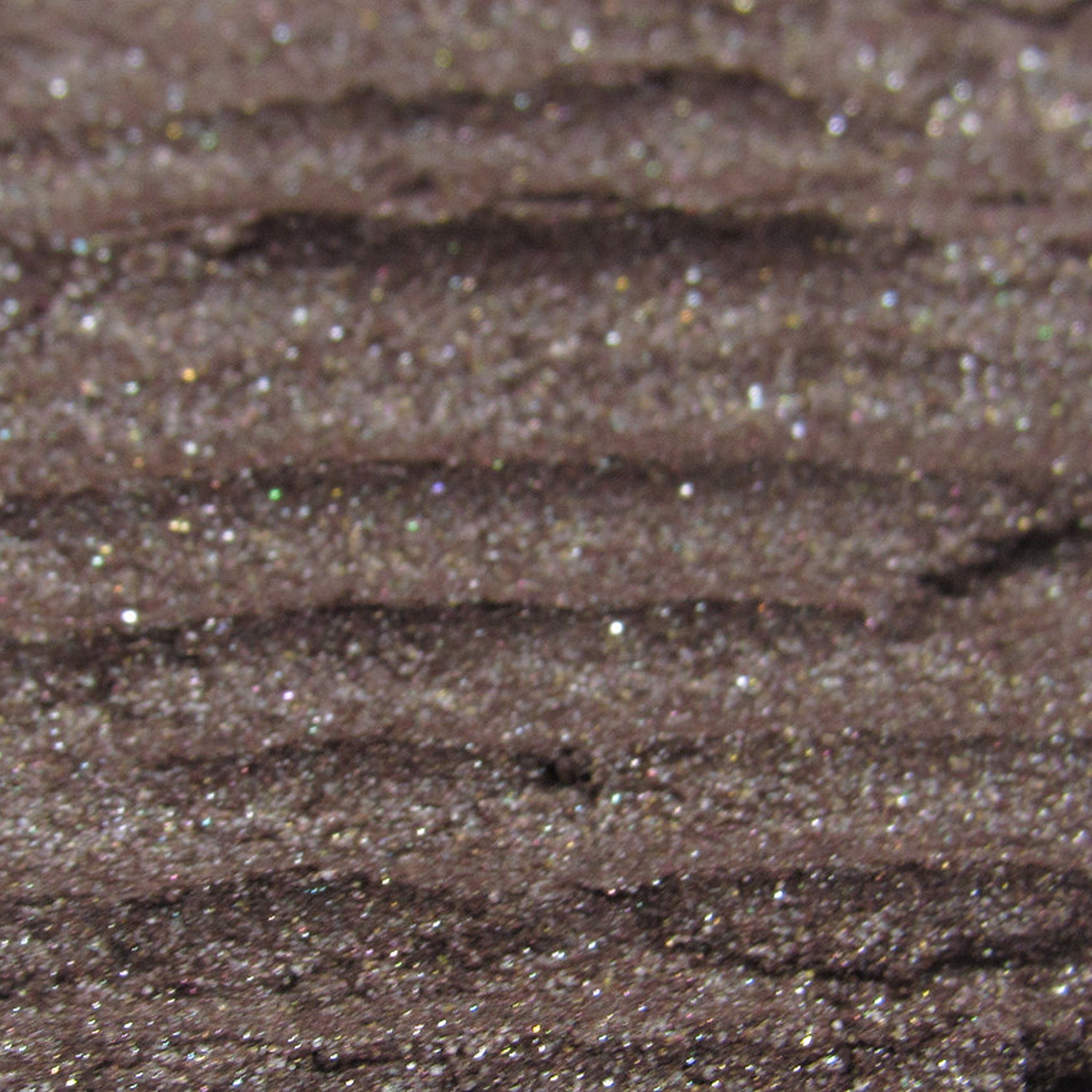 Glitter eyeshadow, brown with shimmer, textured surface close-up