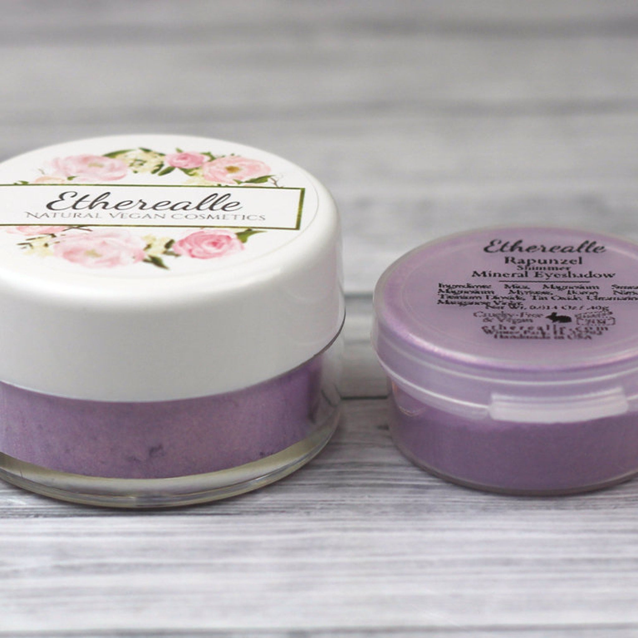 Eyeshadow jars with white lids, floral design, and purple powder, Etherealle brand