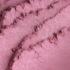 Close-up of Pixie Vegan Mineral Eyeshadow in shimmering rose pink with turquoise sparkles, showing fine powder texture.