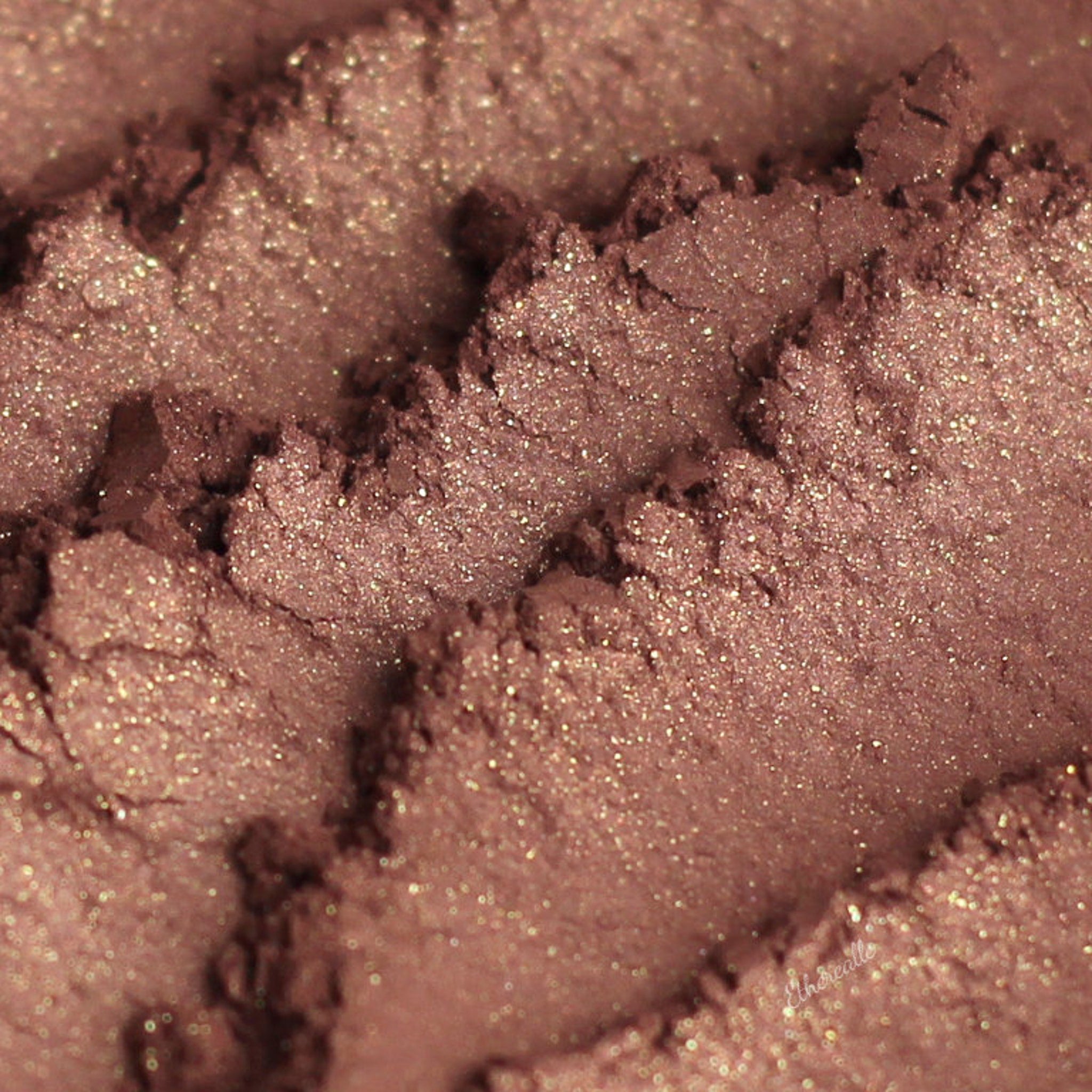 Eye shadow close-up, brown and gold shimmer, textured surface