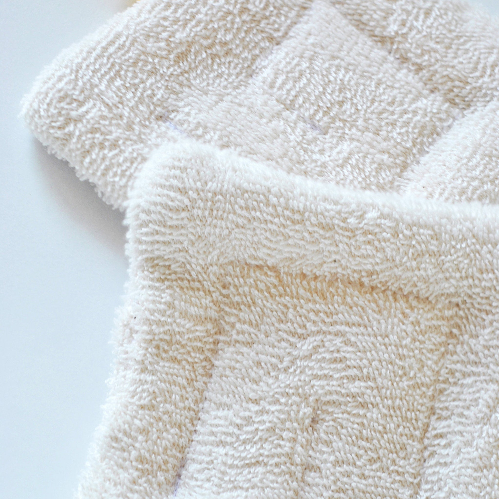 Close-up of organic cotton sponge wipe with textured surface for gentle facial cleansing