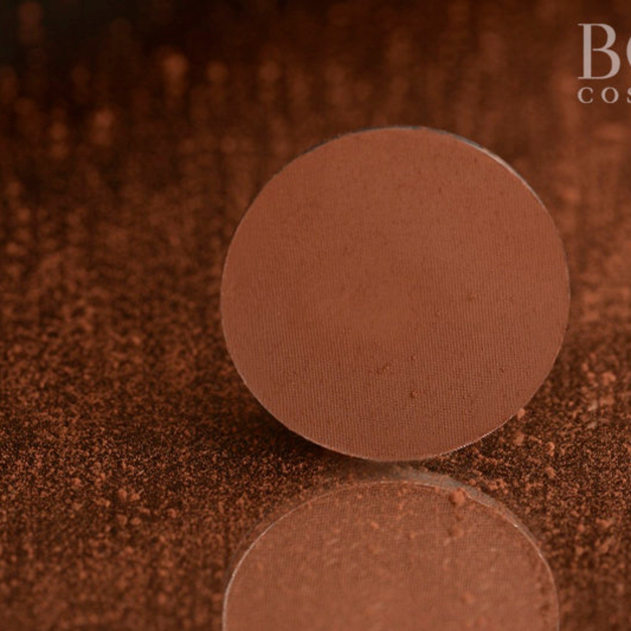 Close-up of fingertips applying matte red-brown eyeshadow to eyelid with smooth blending motion