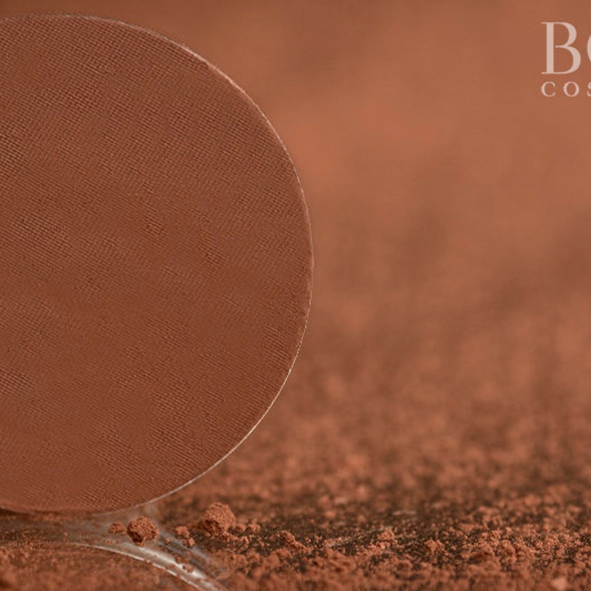 Brown powder eyeshadow with textured surface, and brand name "B" in white text