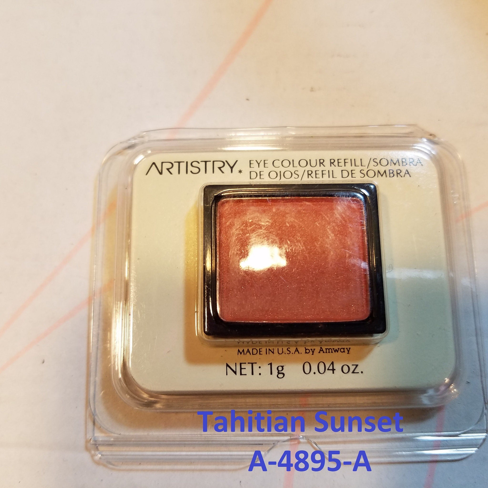 Close-up of matte pink and shimmer gray eyeshadow pans with embossed logo in vintage-style palette