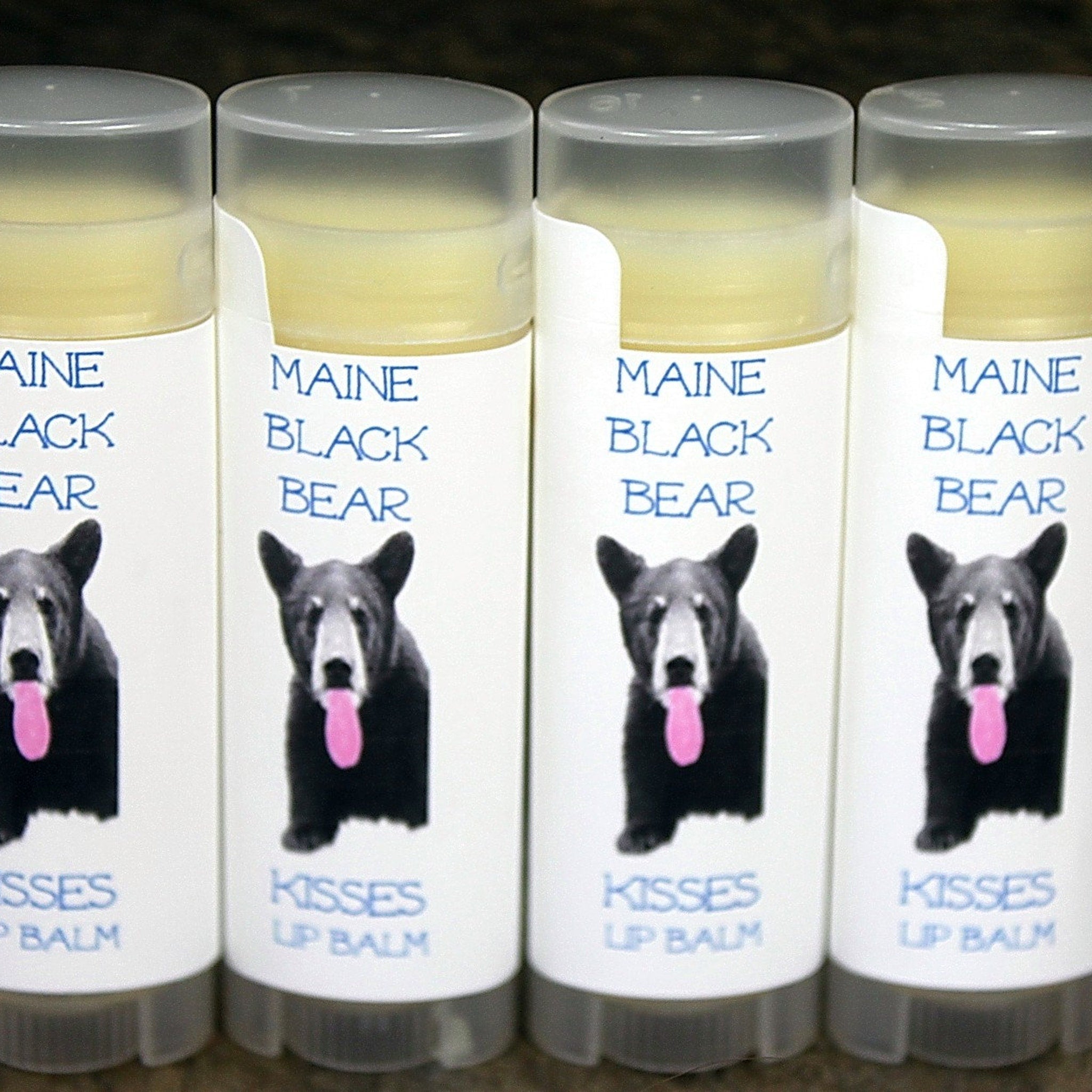 Lip balms with white labels, Maine Black Bear Kisses brand, clear tubes and gray caps