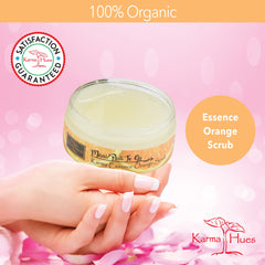 Orange scrub in a glass jar, held by a hand with manicured nails, Karma Hues branding visible