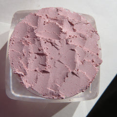 Close-up of pastel pink loose powder eyeshadow with fine shimmer in a seashell-shaped container