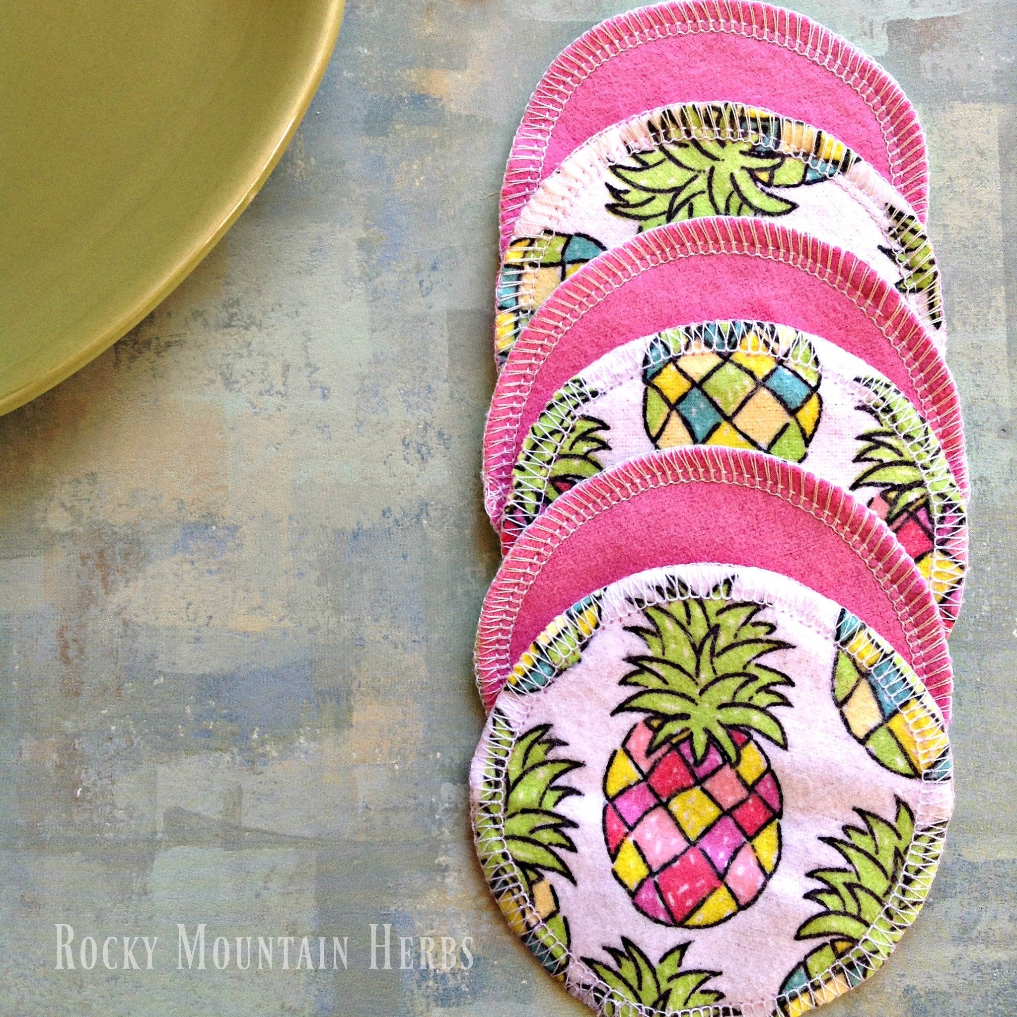Reusable nursing pads with pink trim, pineapple print, and Rocky Mountain Herbs text visible