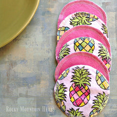 Reusable nursing pads with pink trim, pineapple print, and Rocky Mountain Herbs text visible