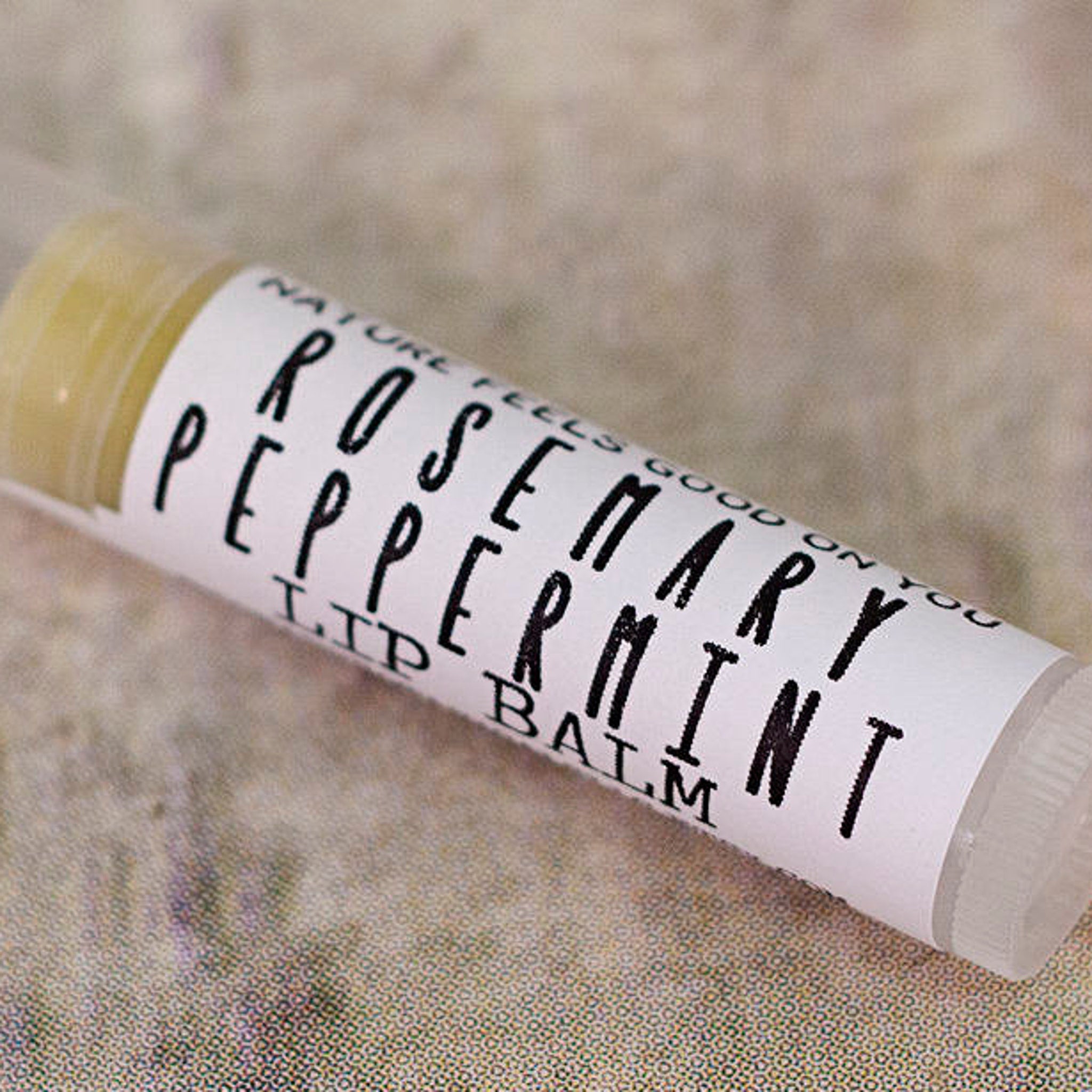 Lip balm tube with white label and black text, on textured background, Redbarn Botanicals