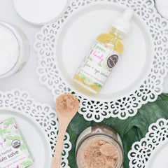 Face serum bottle with yellow liquid, white dropper, and green and pink label on white background