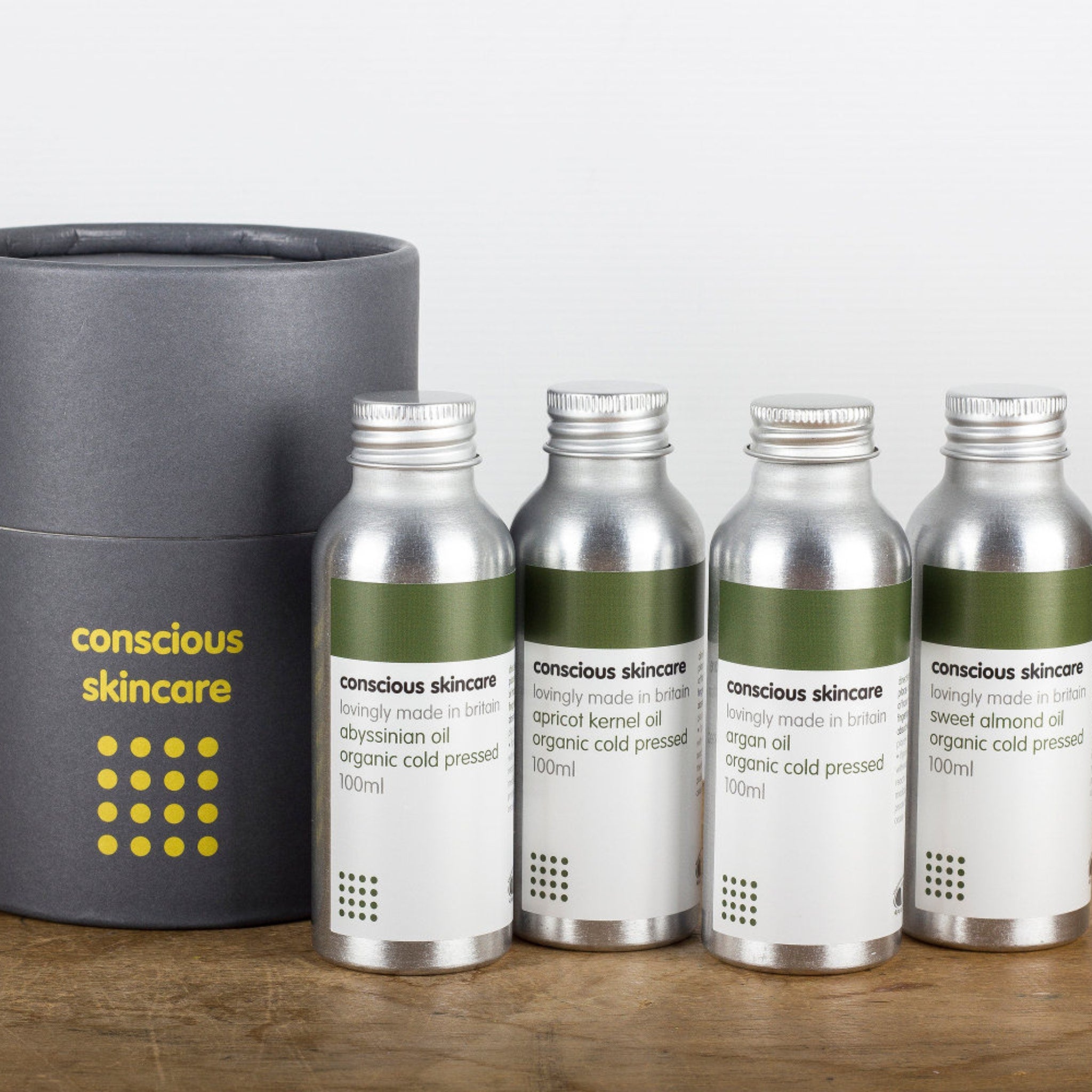Skincare bottles with silver metal, green labels, and brand text, arranged on wooden surface