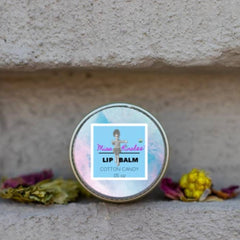 Lip balm tin with iridescent lid, blue label, and Miss Kirolee text, on a textured surface