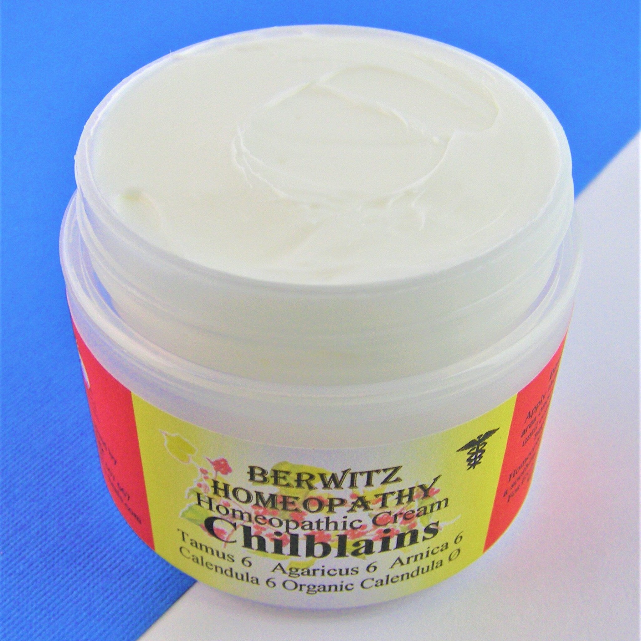 Homeopathic cream in a clear plastic jar with white cream and red and yellow label