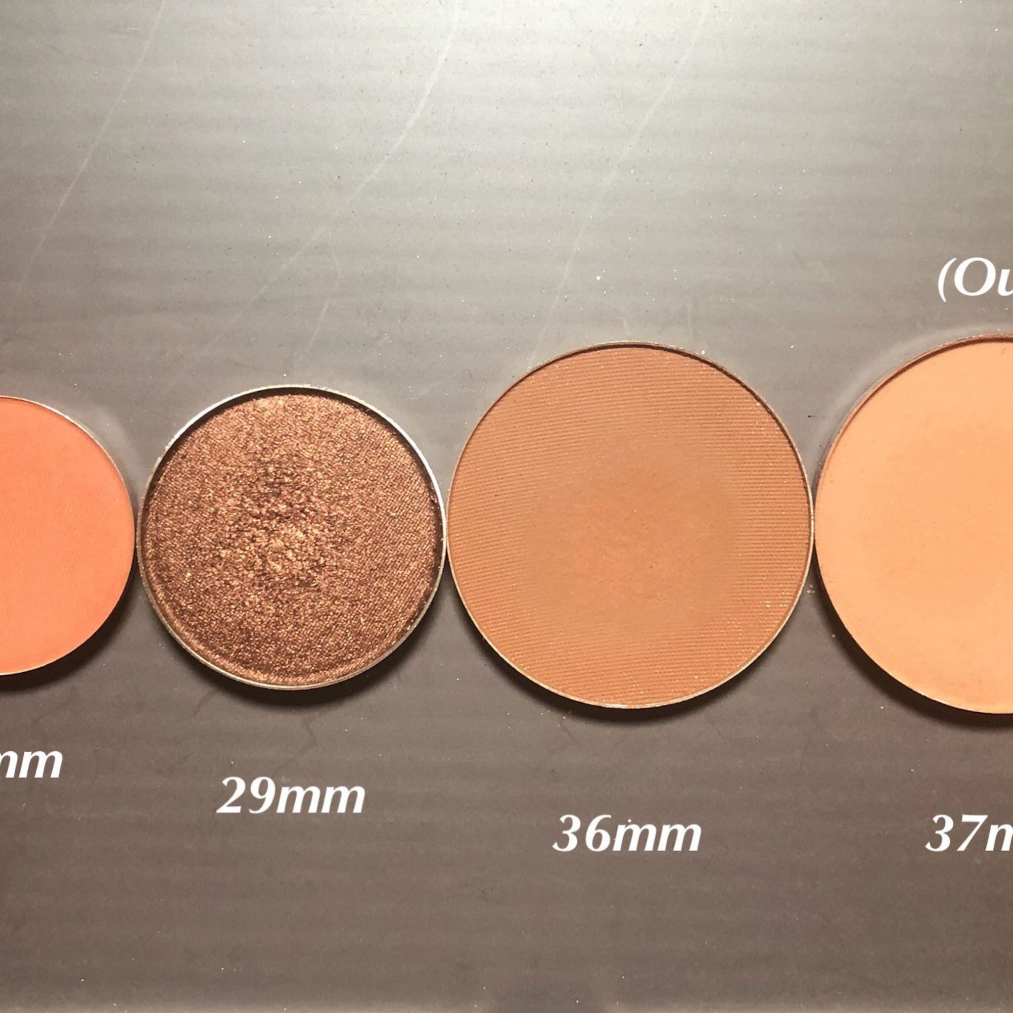 Eyeshadow palette with various shades of orange and brown, metallic and matte finishes, and different sizes