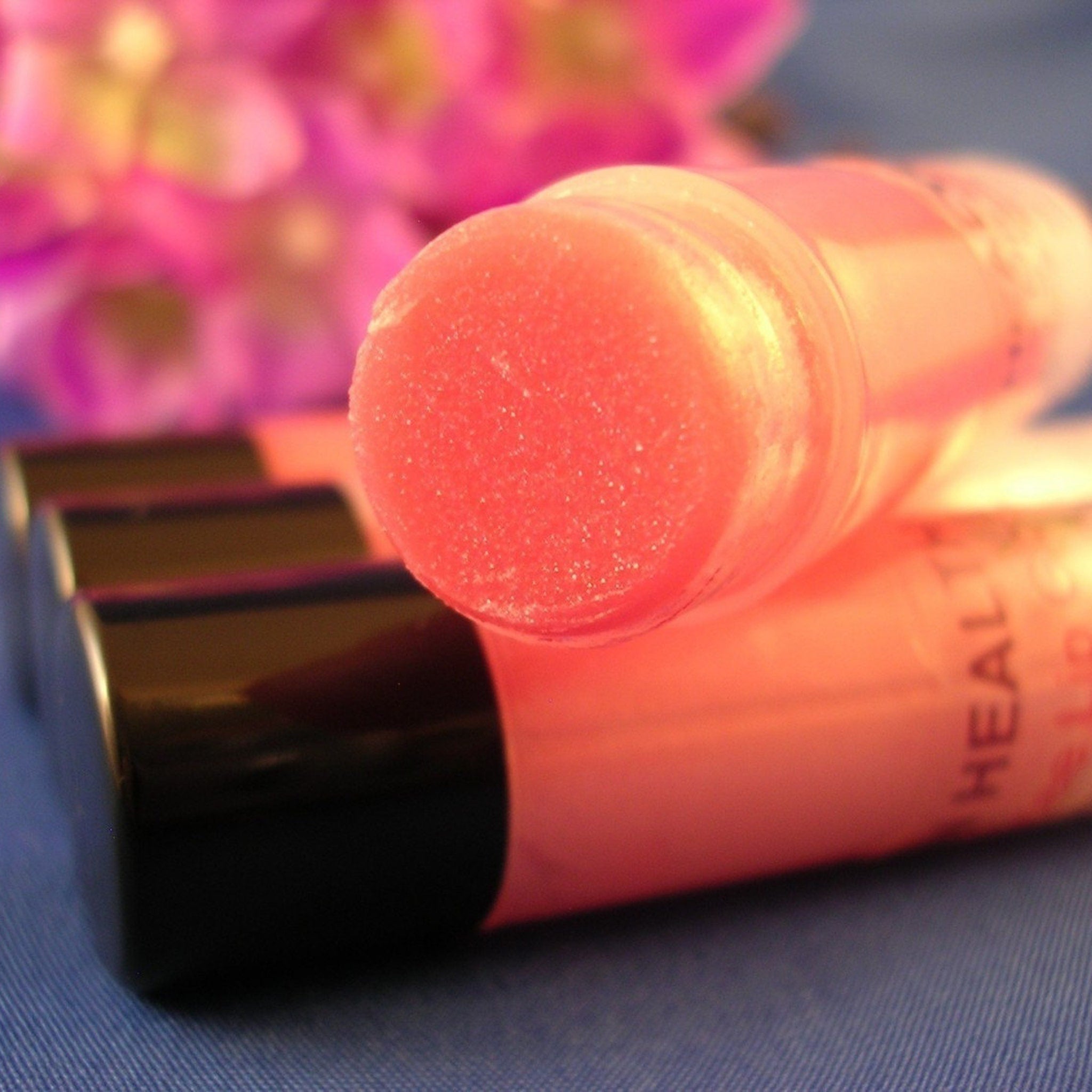 Lip balm tubes with red balm, black caps, and transparent casing, "HEALTH" text visible