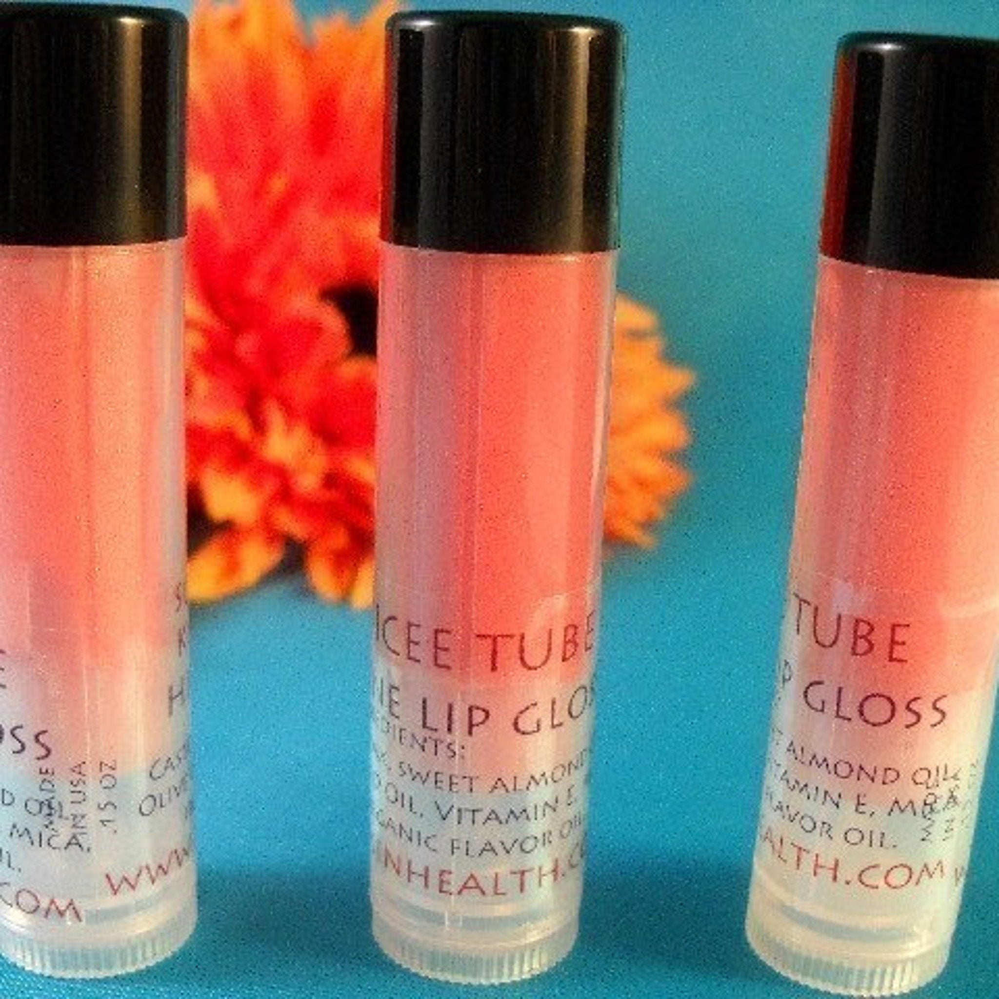 Lip gloss tubes with black caps, clear tubes, and pink gloss inside, Icee Tube brand visible