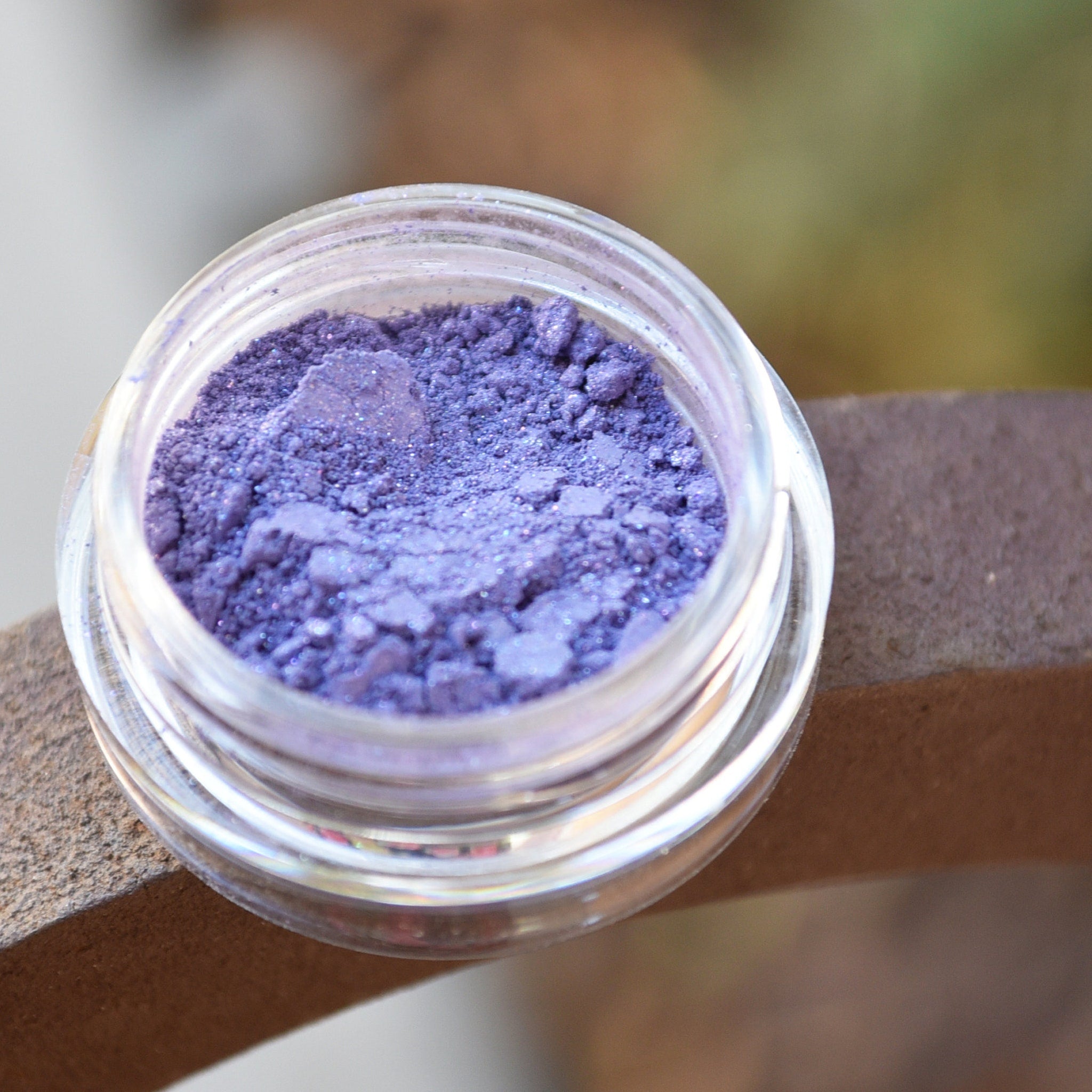 Close-up of pigmented mineral eyeshadow in a jar with sifter, showcasing rich color payoff and fine powder texture