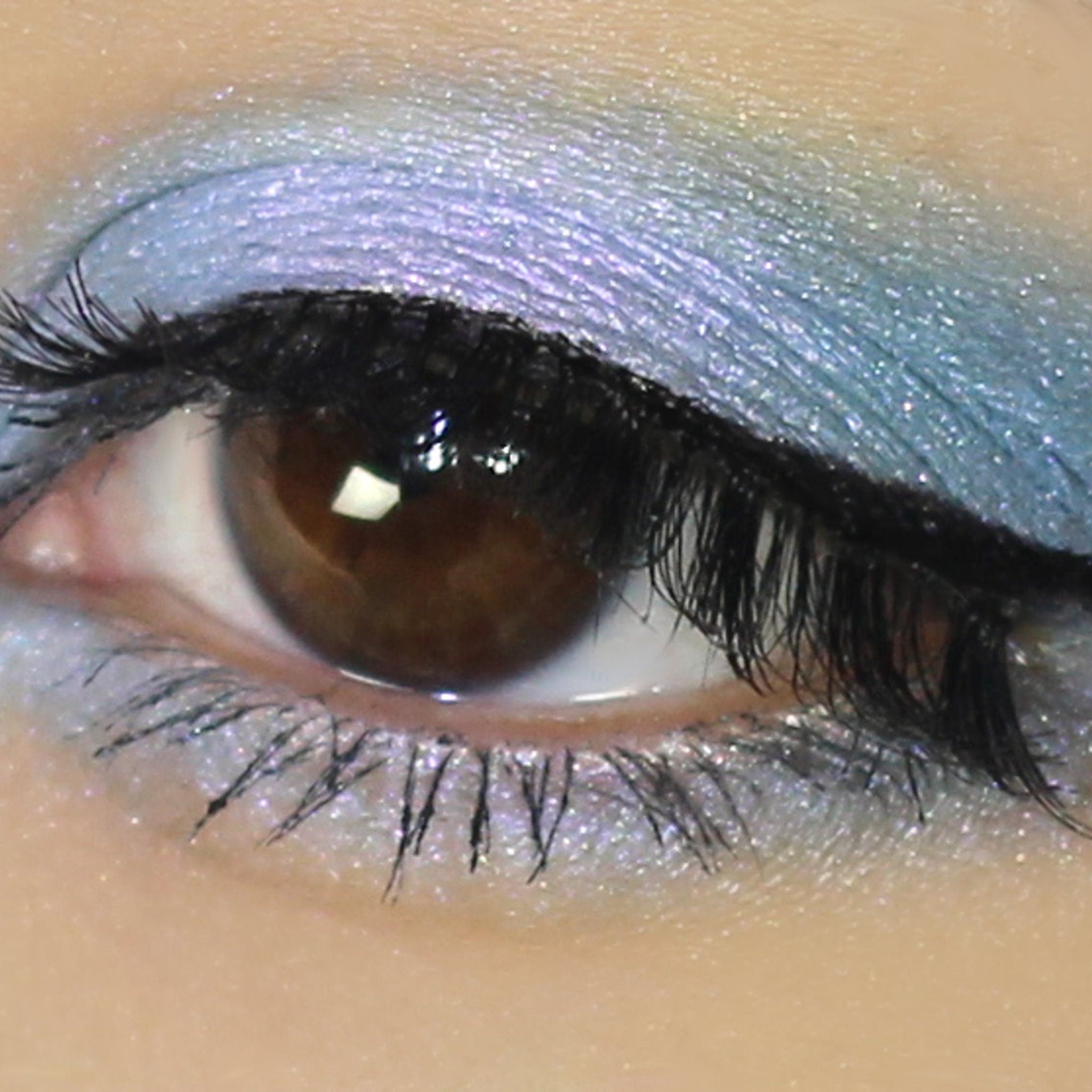 Close-up of vegan mineral eyeshadow in shifting blue-purple duochrome with sparkling metallic finish