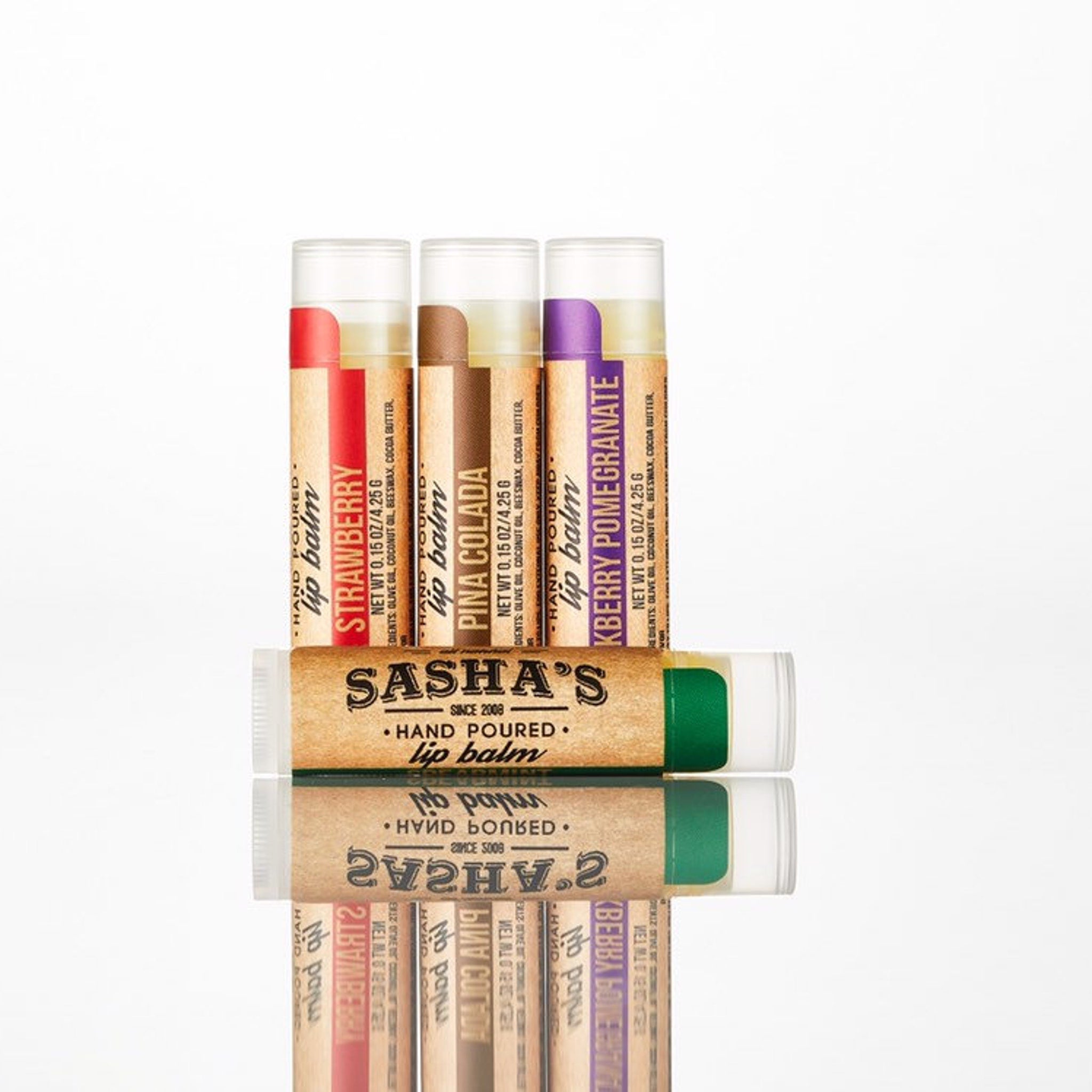 Lip balm tubes with red, brown, and purple labels, Sasha's brand, hand poured