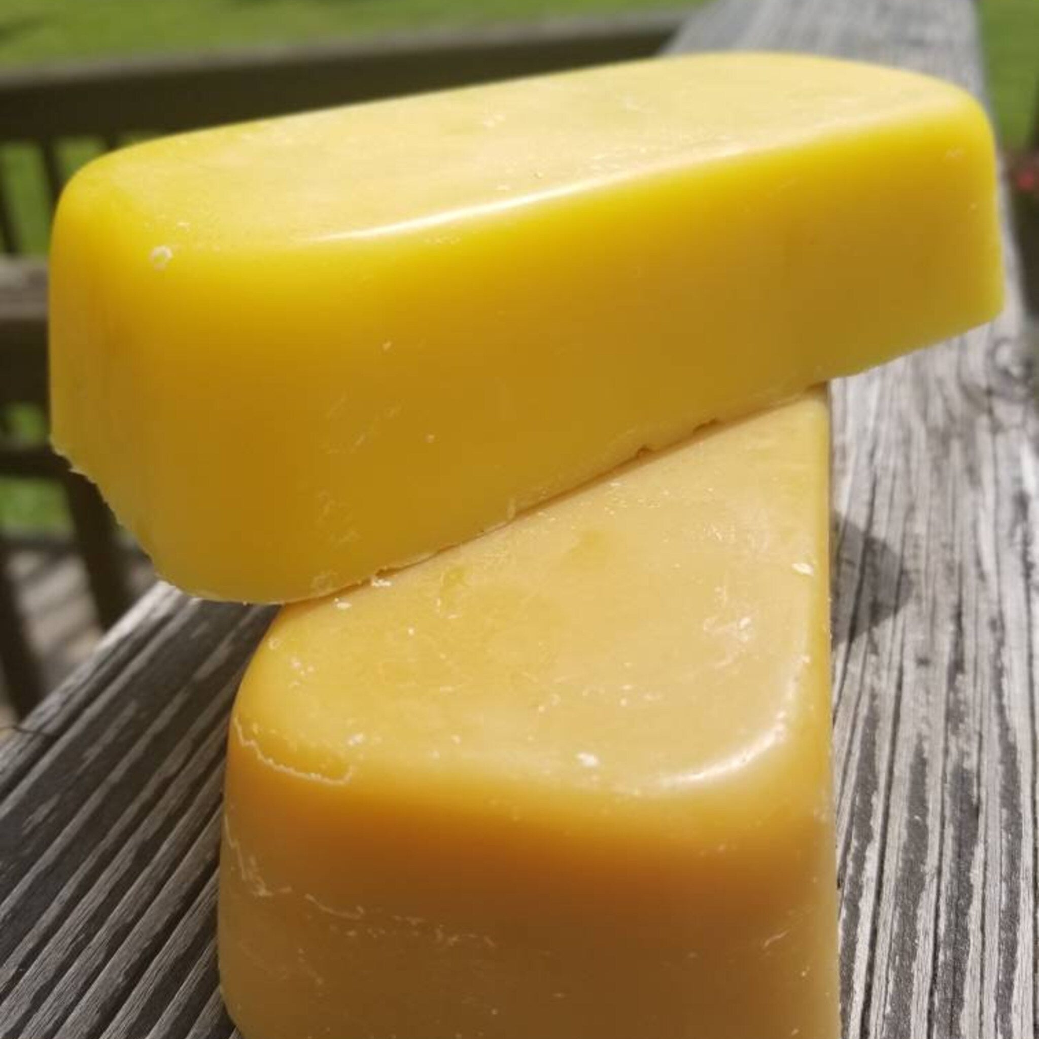 Yellow bars of beeswax, smooth texture, stacked on weathered wood surface