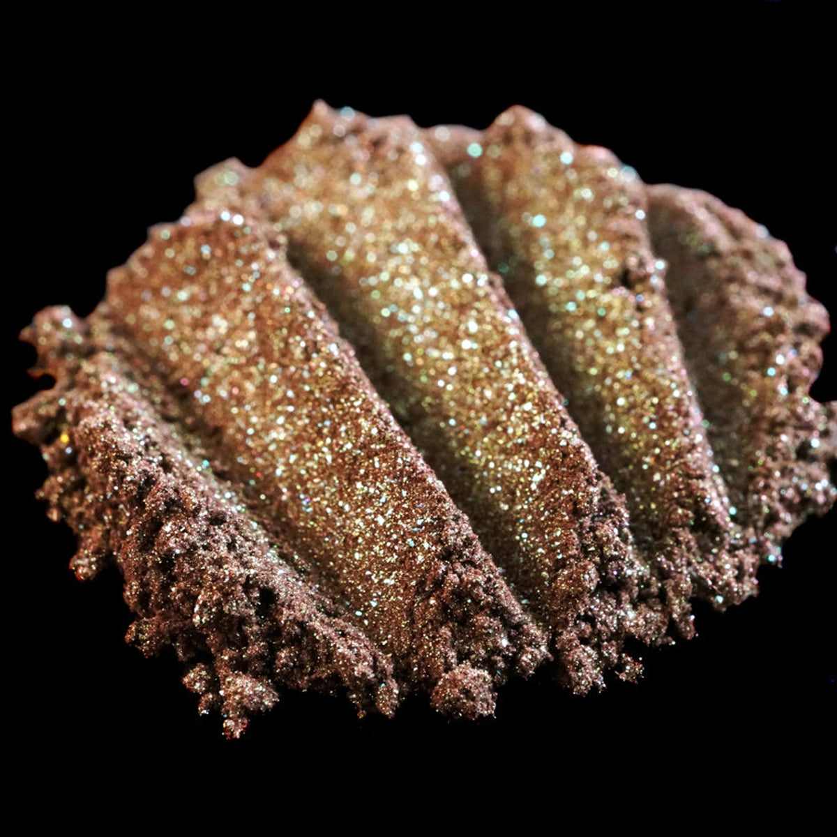 Close-up of duochrome green-brown eyeshadow pan with vegan burgundy base and iridescent shimmer finish