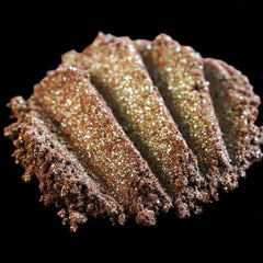 Close-up of duochrome green-brown eyeshadow pan with vegan burgundy base and iridescent shimmer finish